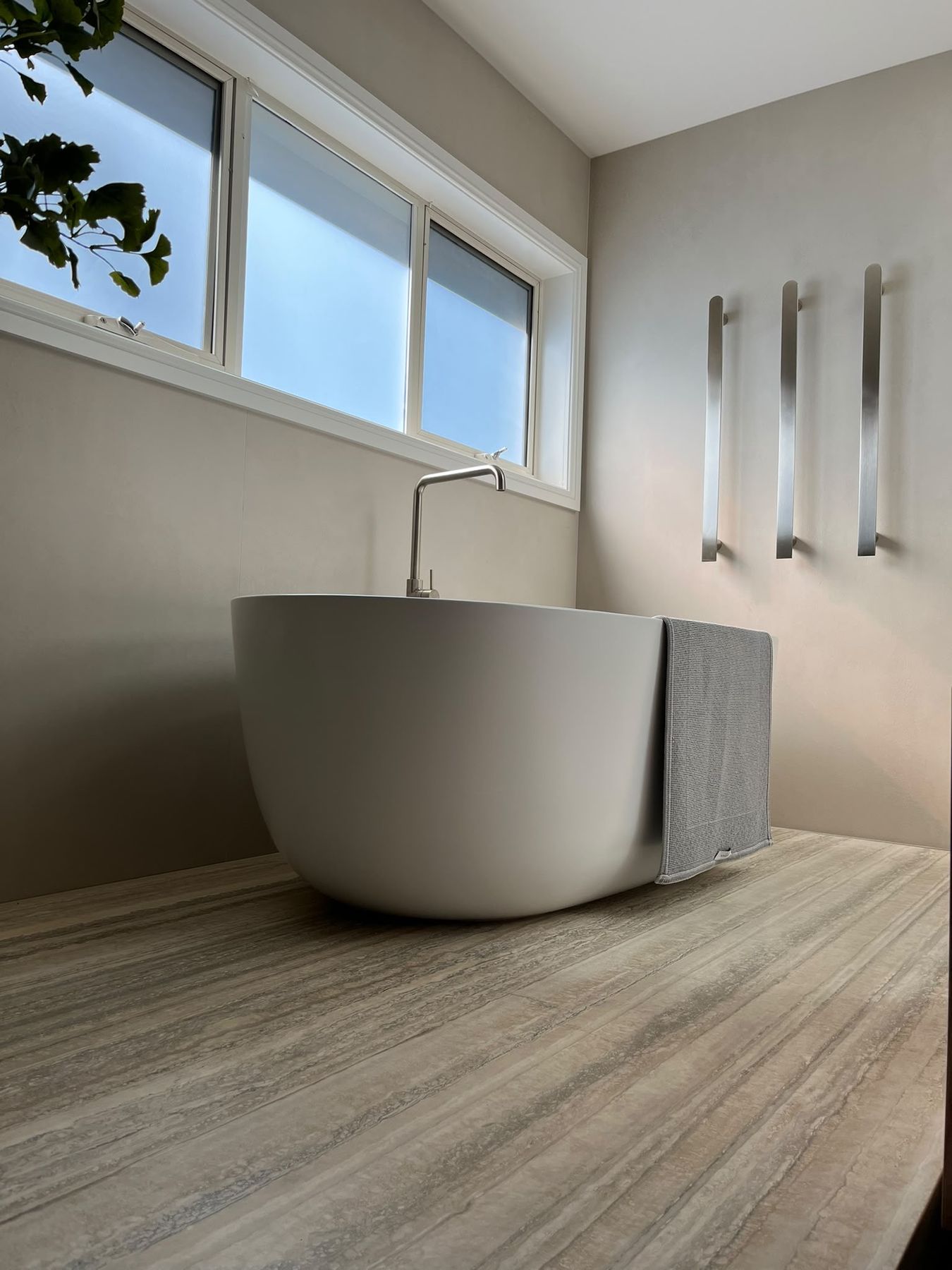 Freestanding bath on travertine flooring with brushed nickel tapware