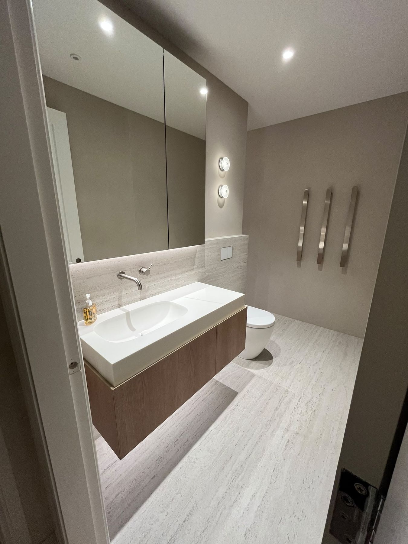 Ensuite with travertine walls and floor, floating oak vanity and wall-hung toilet