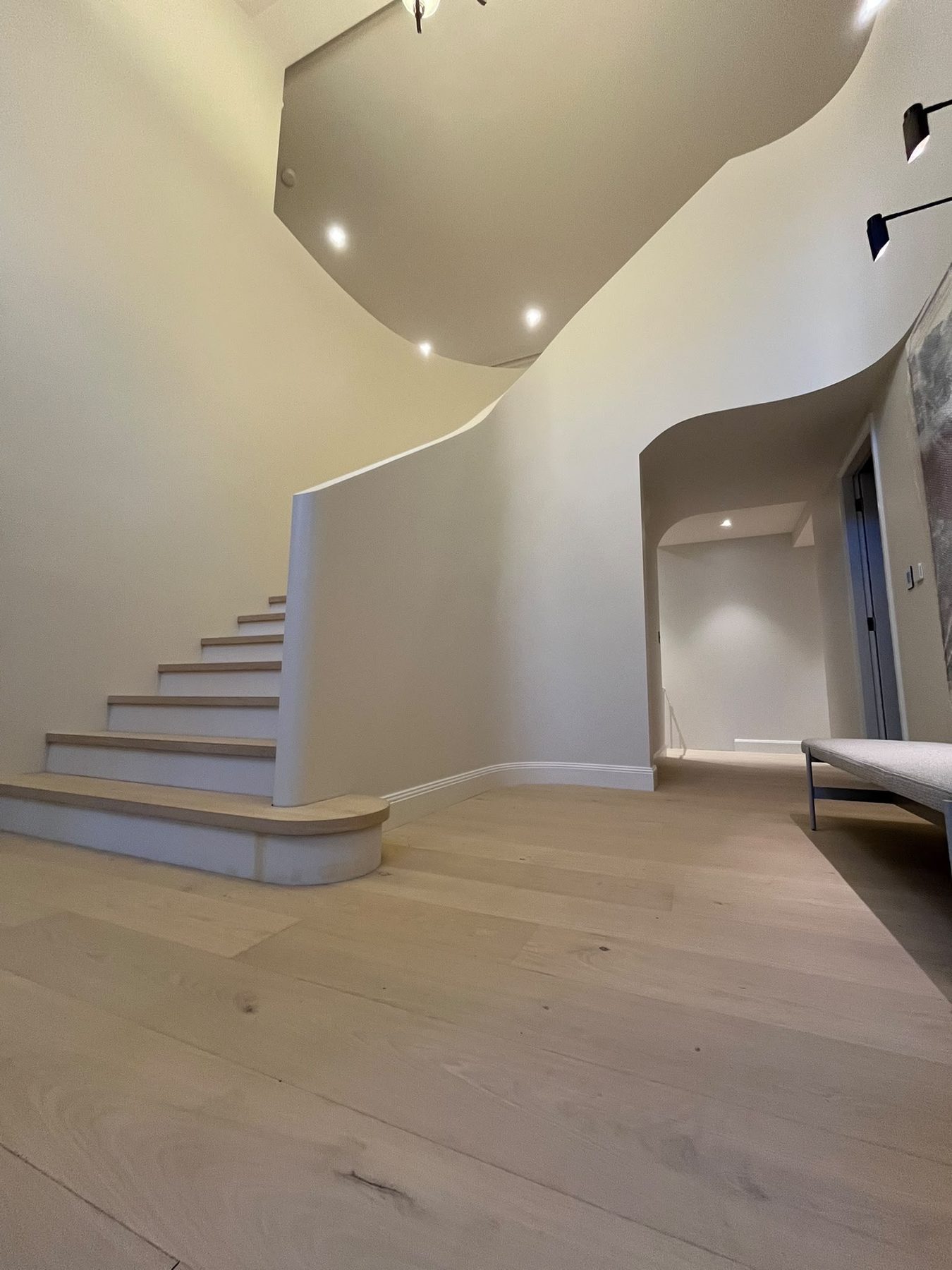 Double-height entry with sculpted curved plaster walls, an oak-treaded staircase and pale oak flooring